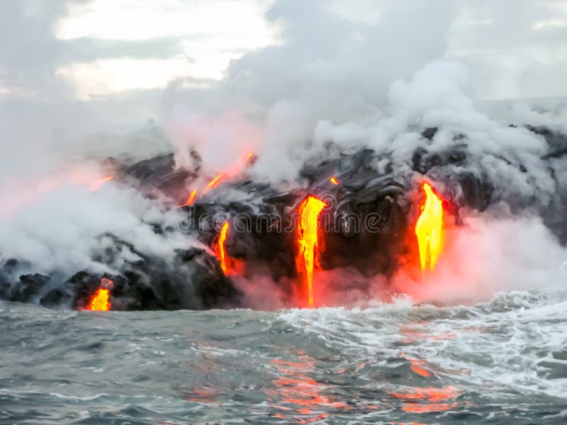 Sea view of Kilauea Volcano in Big Island, Hawaii, United States. A restless volcano that has been in business since 1983. Shot taken at sunset when the lava glows in the dark as jumps into the sea. Sea view of Kilauea Volcano in Big Island, Hawaii, United States. A restless volcano that has been in business since 1983. Shot taken at sunset when the lava glows in the dark as jumps into the sea.