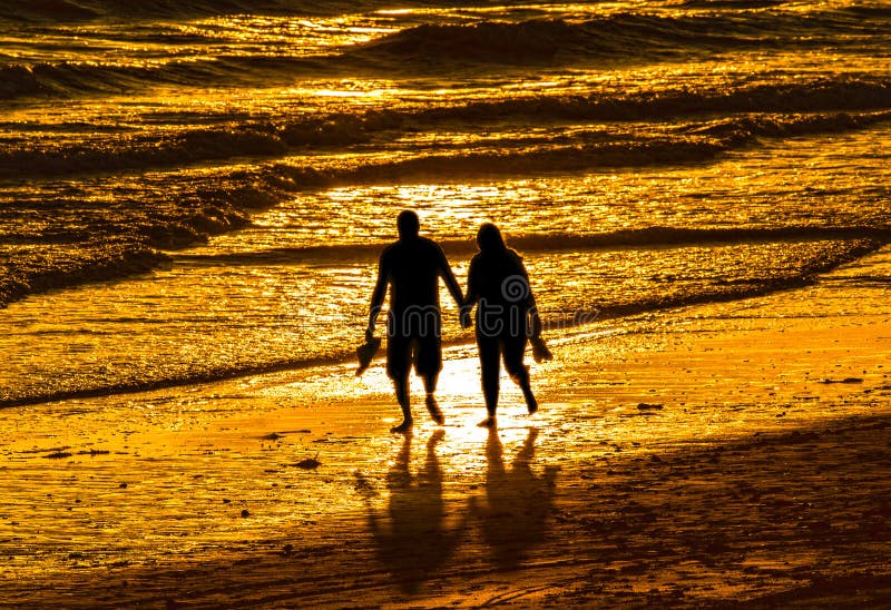 Couple walking holding hands on golden sunset beach. Couple walking holding hands on golden sunset beach.