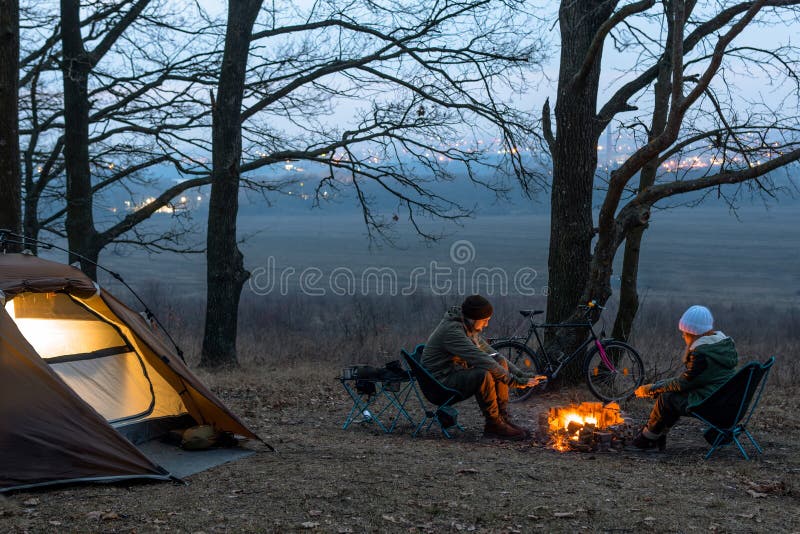 Kilku ludzi, mężczyzna i kobieta siedzą na krzesłach przy ognisku Zimna jesienna noc w lesie fotografia stock