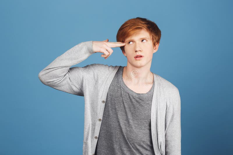 Kill me please. Young good-looking tired male student with ginger hair in casual gray outfit making gun gesture with royalty free stock photo Kill me please. Young good-looking tired male student with ginger hair in casual gray outfit making gun gesture with royalty free stock photo