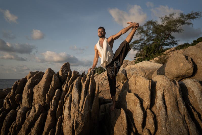 Killen som gör yoga lägger ut på vassa stenar nära stranden i Thailand arkivbilder