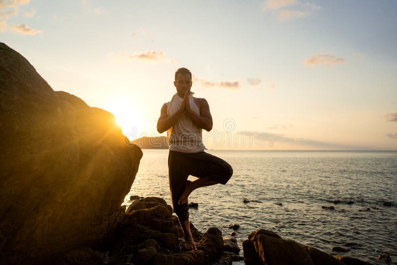 Killen som gör yoga lägger ut på vassa stenar nära stranden i Thailand arkivfoton