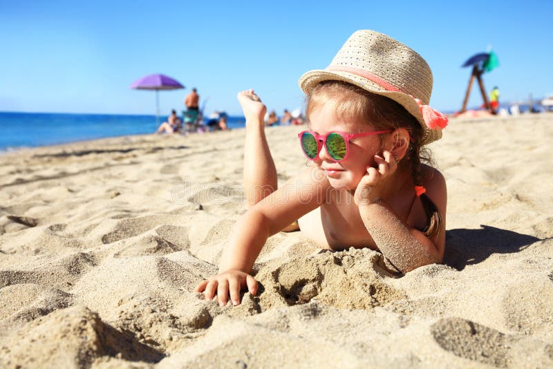 Kind, das auf sandigem Strand nahe blauem Meer liegt Sommerferien und gesundes Lebensstilkonzept lizenzfreies stockfoto