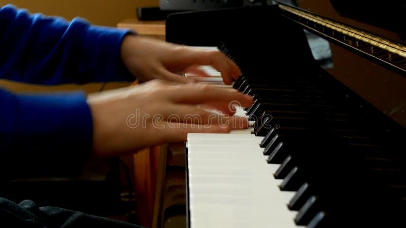Kind, das Klavier spielt Nahe hohe Seitenansicht von jungen H?nden und von Fingern, die ein Lied auf den Schl?sseln spielen
