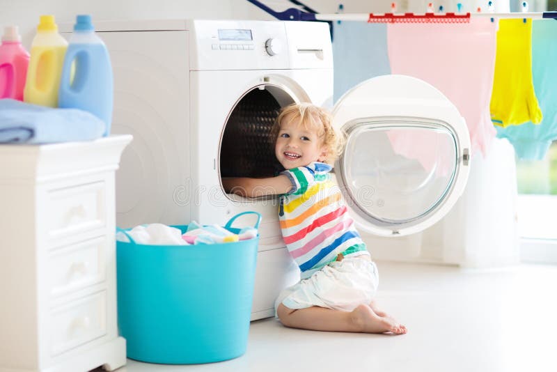 Kind in der Waschküche mit Waschmaschine stockfoto