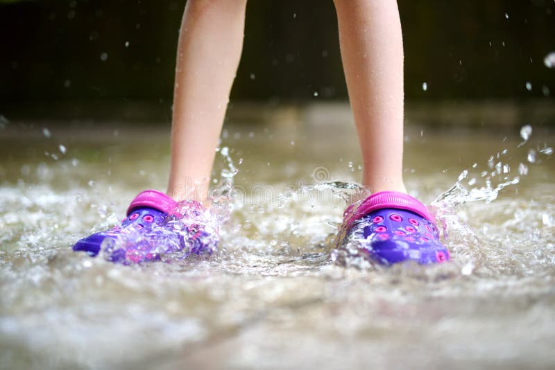 Kind die rubberschoenen dragen die in een vulklei springen stock afbeelding Kind die rubberschoenen dragen die in een vulklei springen stock afbeelding