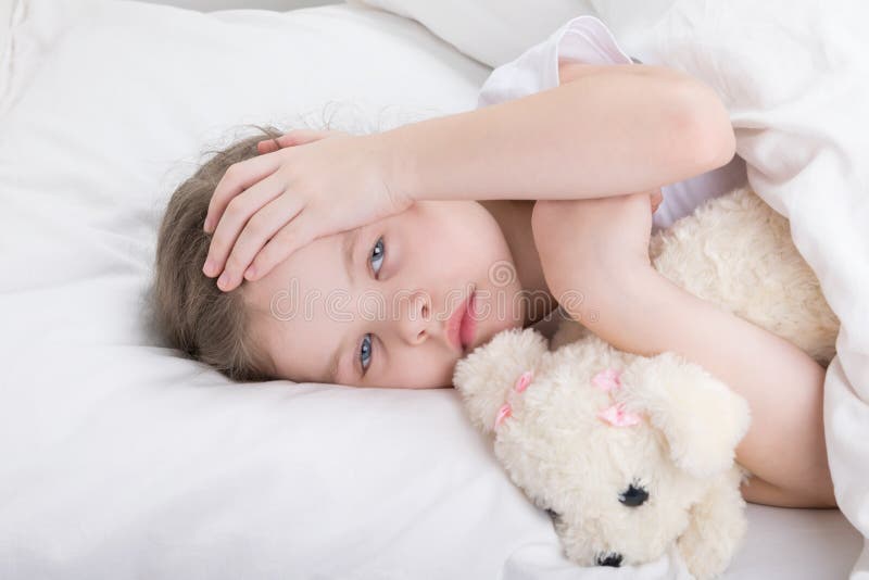 Kind in einem weißen Bett beschwert sich von Kopfschmerzen