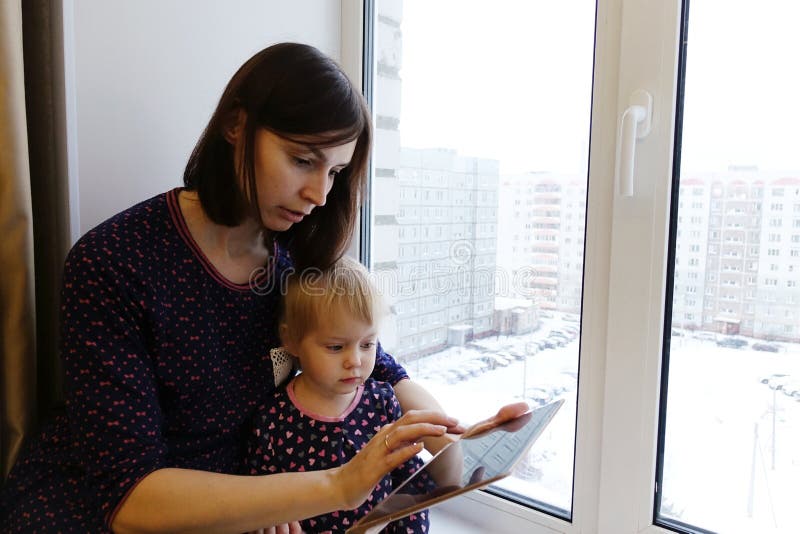 Kind mit der jungen Mutter, die auf der Tablette spielt stockbilder Kind mit der jungen Mutter, die auf der Tablette spielt stockbilder