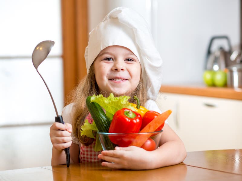 Child girl weared as cook with vegetables at kitchen. Child girl weared as cook with vegetables at kitchen