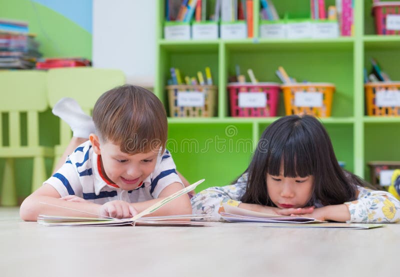 Kind zwei legen auf Boden- und Lesegeschichtenbuch in der Vorschulbibliothek, Kindergartenschulbildungskonzept nieder lizenzfreies stockfoto Kind zwei legen auf Boden- und Lesegeschichtenbuch in der Vorschulbibliothek, Kindergartenschulbildungskonzept nieder lizenzfreies stockfoto