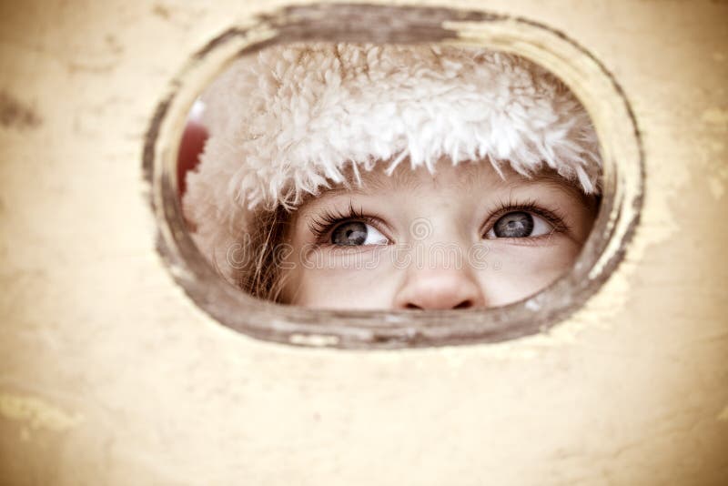 Child look out of hole in wooden background. Shallow depth of field. Child look out of hole in wooden background. Shallow depth of field