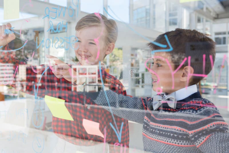 Kinder als Unternehmensleiter, die über whiteboard sich besprechen lizenzfreie stockfotografie Kinder als Unternehmensleiter, die über whiteboard sich besprechen lizenzfreie stockfotografie