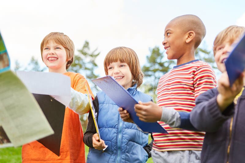 Happy children on a treasure hunt as a scavenger hunt in nature with clipboard. Happy children on a treasure hunt as a scavenger hunt in nature with clipboard