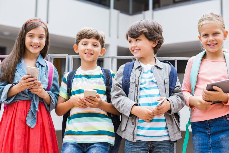 Kinder, die den Handy und digitale Tablette stehend auf Schulterrasse halten stockbilder Kinder, die den Handy und digitale Tablette stehend auf Schulterrasse halten stockbilder