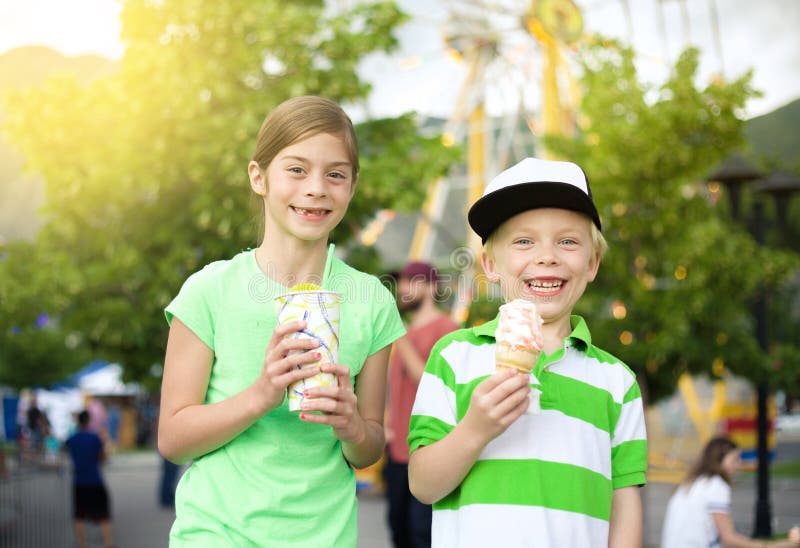 Kinder, die Eiscreme und Festlichkeiten am Karneval essen lizenzfreie stockfotos Kinder, die Eiscreme und Festlichkeiten am Karneval essen lizenzfreie stockfotos