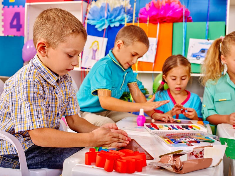 Kinder, die herein farbiges Papier und Kleber auf Tabelle halten lizenzfreie stockfotografie Kinder, die herein farbiges Papier und Kleber auf Tabelle halten lizenzfreie stockfotografie