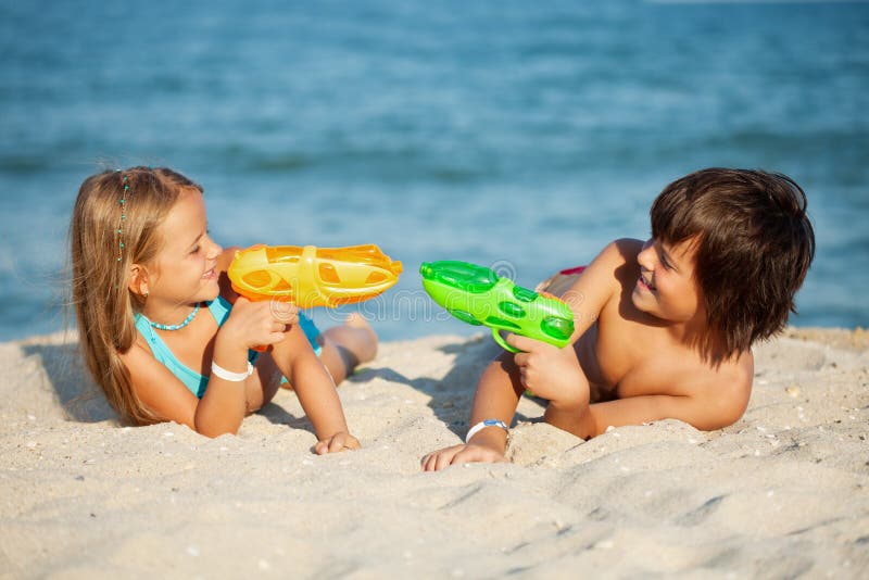 Kinder, die Spaß mit Wasserpistolen auf dem Strand haben stockbilder Kinder, die Spaß mit Wasserpistolen auf dem Strand haben stockbilder