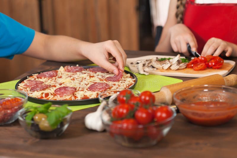 Kinder, die zu Hause eine Pizza machen lizenzfreie stockbilder Kinder, die zu Hause eine Pizza machen lizenzfreie stockbilder
