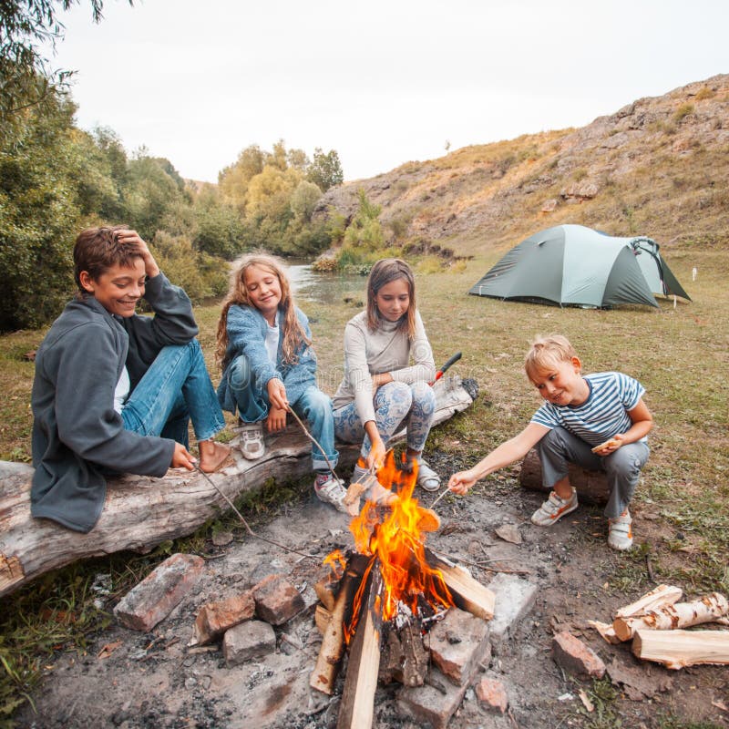 Kinder im Lager durch das Feuer lizenzfreies stockbild Kinder im Lager durch das Feuer lizenzfreies stockbild