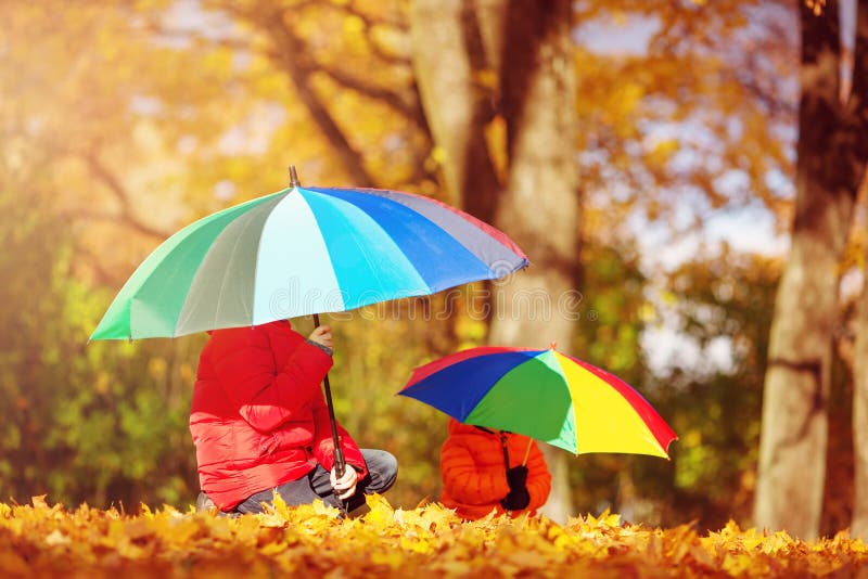 Kinder mit Regenschirmen im schönen Herbsttag lizenzfreie stockfotografie