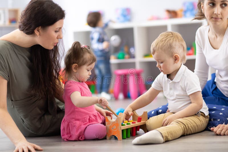 Kinder spielen im Kindergarten oder im Kindertagesstätten unter der Aufsicht von Müttern