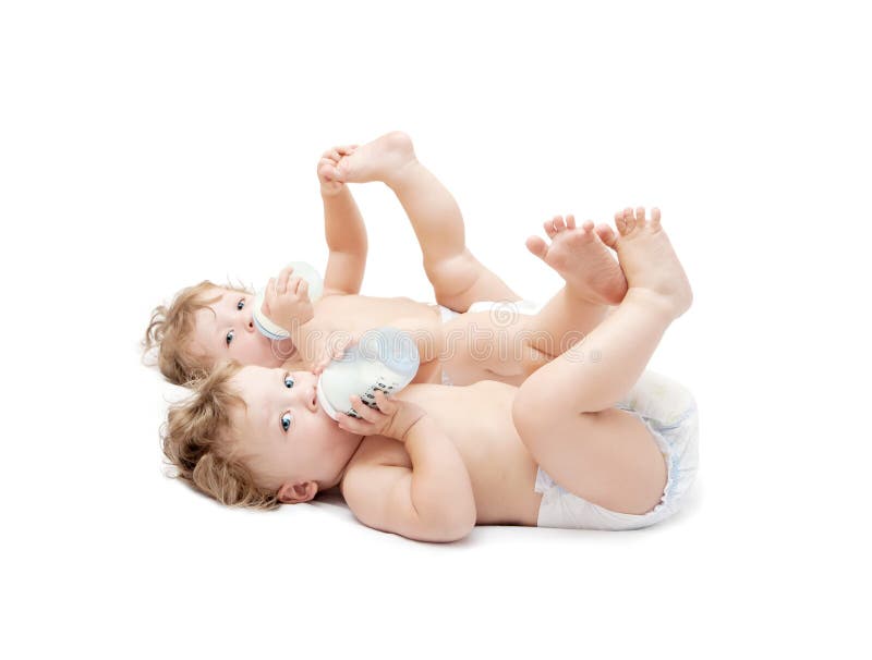 Kinderen de tweelingen die zuigen melkflessen liggen stock fotografie Kinderen de tweelingen die zuigen melkflessen liggen stock fotografie