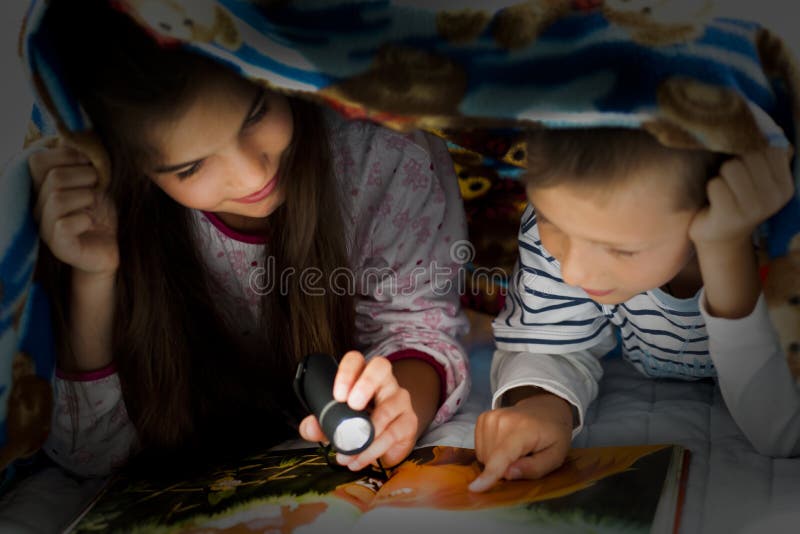 Kinderen die bij nacht lezen stock foto Kinderen die bij nacht lezen stock foto