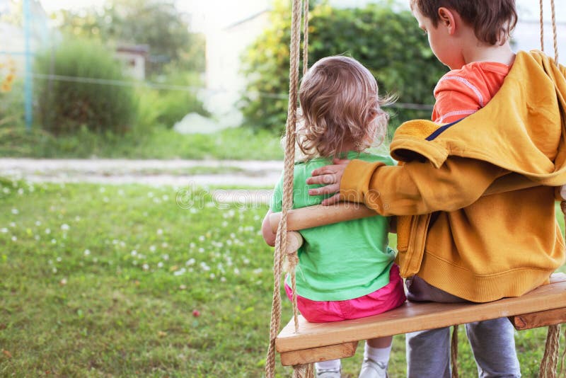 Kinderen die op een schommeling in de tuin zitten stock fotografie Kinderen die op een schommeling in de tuin zitten stock fotografie