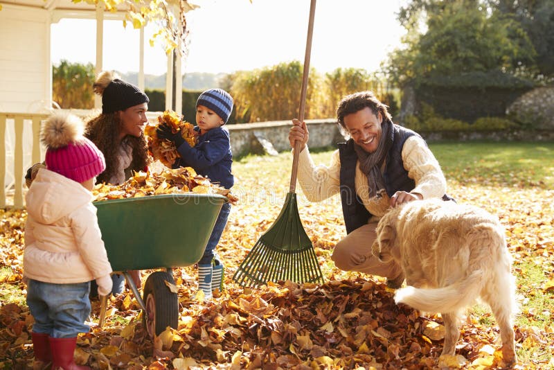 Kinderen die Ouders helpen om Autumn Leaves In Garden te verzamelen royalty-vrije stock fotografie Kinderen die Ouders helpen om Autumn Leaves In Garden te verzamelen royalty-vrije stock fotografie