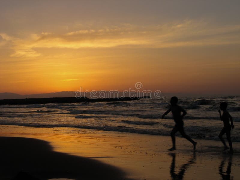 Kinderen die overzeese strandzonsondergang spelen Twee jongens die op het strand in de zonsondergangtijd lopen royalty-vrije stock afbeelding Kinderen die overzeese strandzonsondergang spelen Twee jongens die op het strand in de zonsondergangtijd lopen royalty-vrije stock afbeelding
