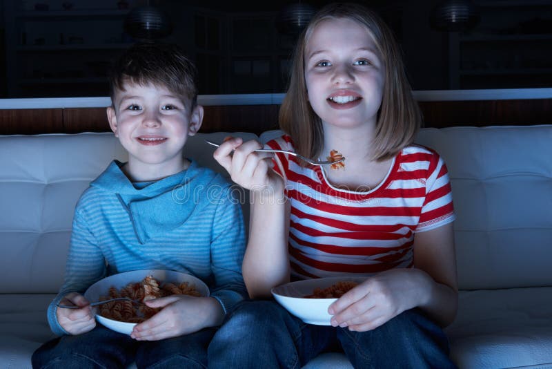 Kinderen die van Maaltijd genieten terwijl het Letten van op TV stock afbeeldingen Kinderen die van Maaltijd genieten terwijl het Letten van op TV stock afbeeldingen