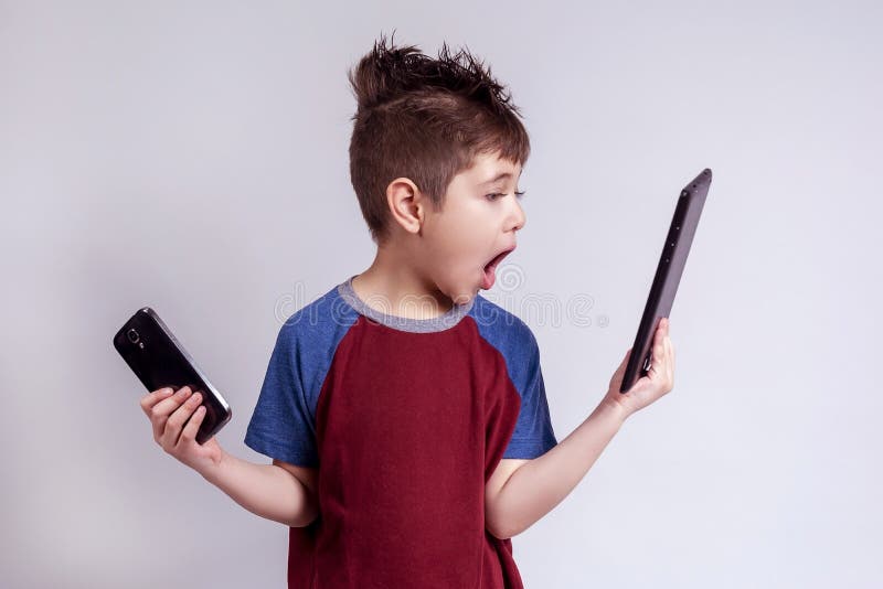 Child reacting to a tablet and holding a cell phone