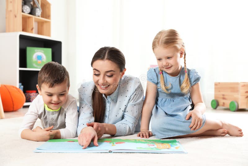 Kindergarten teacher reading book to children. Learning and playing royalty free stock photos Kindergarten teacher reading book to children. Learning and playing royalty free stock photos