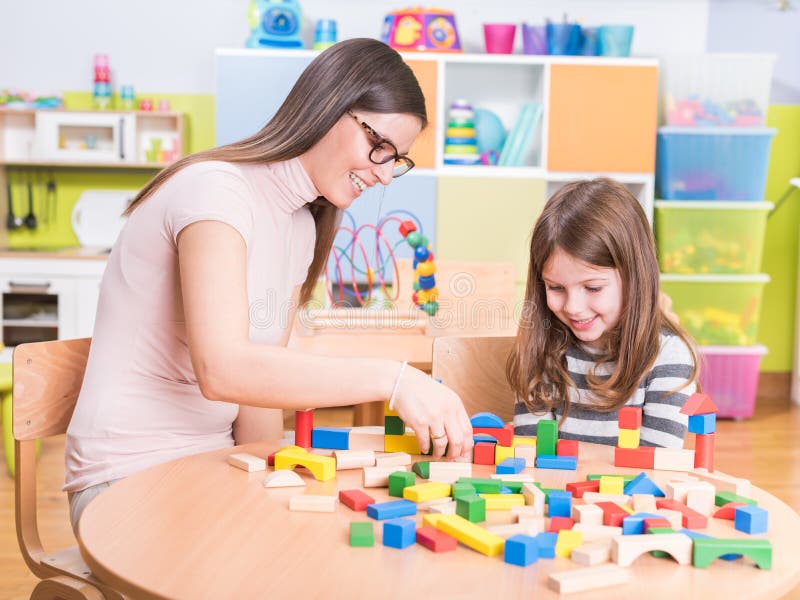 Kindergärtnerin und nettes lächelndes Mädchen-Spielen lizenzfreie stockfotografie Kindergärtnerin und nettes lächelndes Mädchen-Spielen lizenzfreie stockfotografie