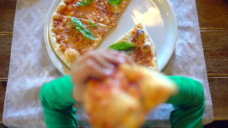 Kinderhände, die eine Scheibe der Pizza von einer weißen Platte im Restaurant, Café nehmen Nahaufnahme Wenig Junge oder Mädchen n