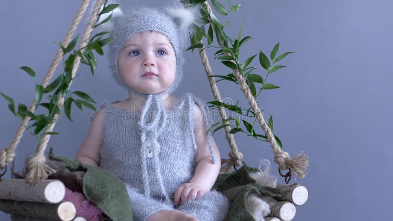 Kinderkostüm, Kind in der Eichhörnchenklage sitzt auf dem Rebschwingen, das mit dem Grün auf blauem Hintergrund verziert wird