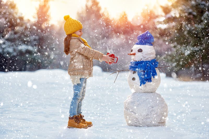 Kindermädchen, das mit einem Schneemann plaing ist lizenzfreies stockbild Kindermädchen, das mit einem Schneemann plaing ist lizenzfreies stockbild