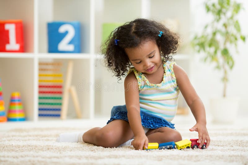 Kindermädchen, das Spielwaren am Kindergartenraum spielt lizenzfreies stockbild