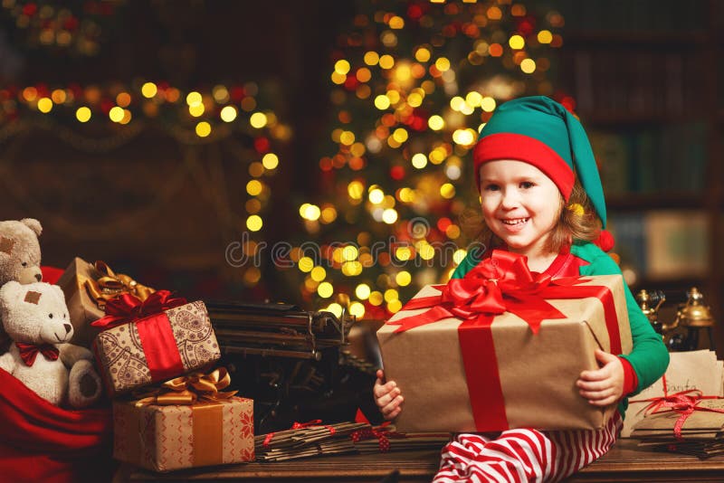 Kindermädchen-Elfenhelfer von Sankt mit einem Weihnachtsgeschenk stockbild Kindermädchen-Elfenhelfer von Sankt mit einem Weihnachtsgeschenk stockbild