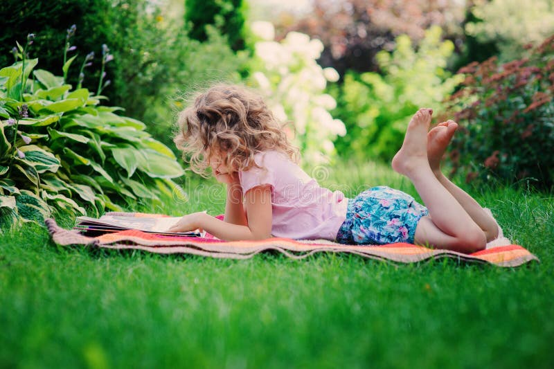 Kindermädchen-Lesebuch im Garten, lernend auf Sommerferien stockbild