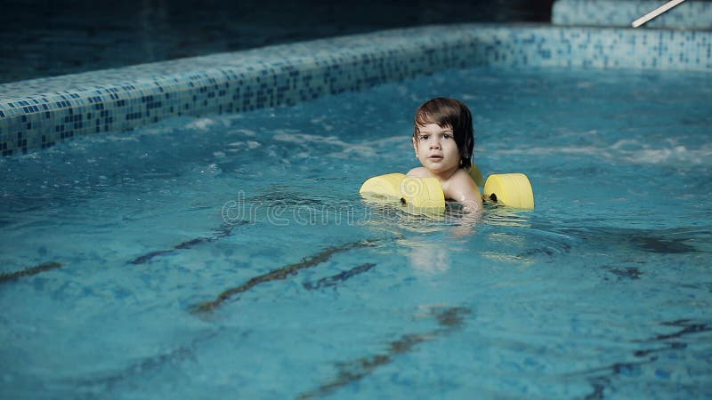 Kinderschwimmen im Pool Schwimmen des kleinen Jungen im Pool in der Freizeitmitte