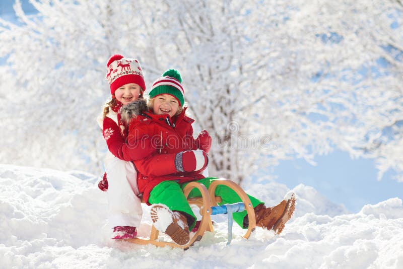 Kinderspiel im Schnee Winterschlittenfahrt für Kinder lizenzfreie stockbilder Kinderspiel im Schnee Winterschlittenfahrt für Kinder lizenzfreie stockbilder