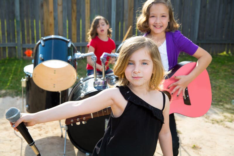 Kindersängermädchen, das Liveband im Hinterhof spielend singt lizenzfreies stockbild Kindersängermädchen, das Liveband im Hinterhof spielend singt lizenzfreies stockbild
