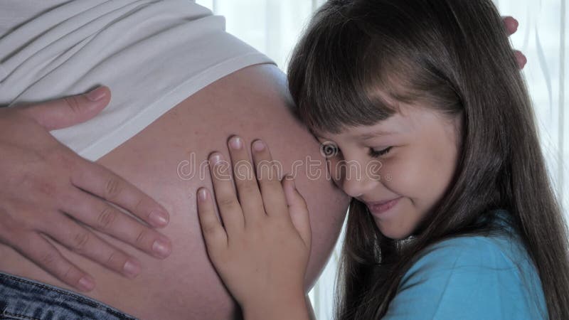 Kinderzoen moeder maag luistert naar hoe baby zich in de buik van zwangere vrouwen beweegt