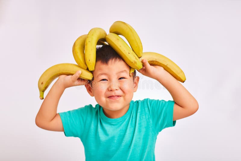 Kindjongen in een turkoois overhemd, hoofd op bananen - fruit en gezond voedsel royalty-vrije stock afbeeldingen Kindjongen in een turkoois overhemd, hoofd op bananen - fruit en gezond voedsel royalty-vrije stock afbeeldingen