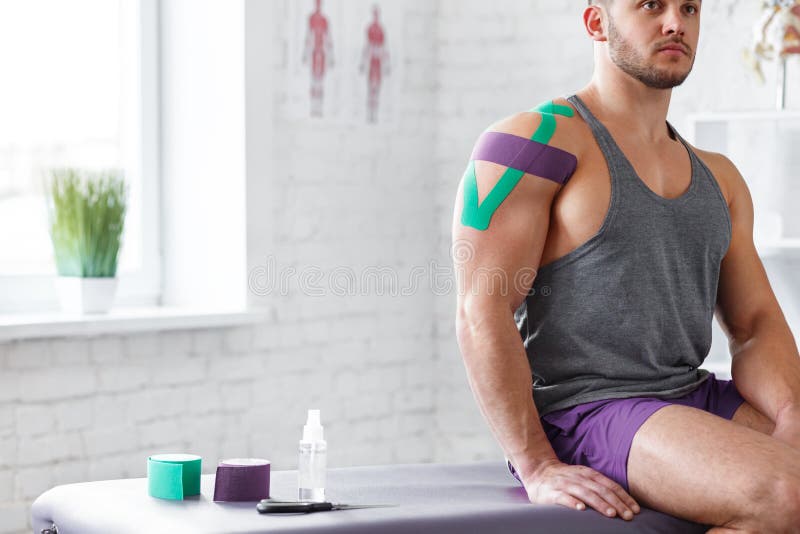 Kinesiology taping. Kinesiology tape on patient shoulder. Injured shoulder treatment of young male athlete. Post