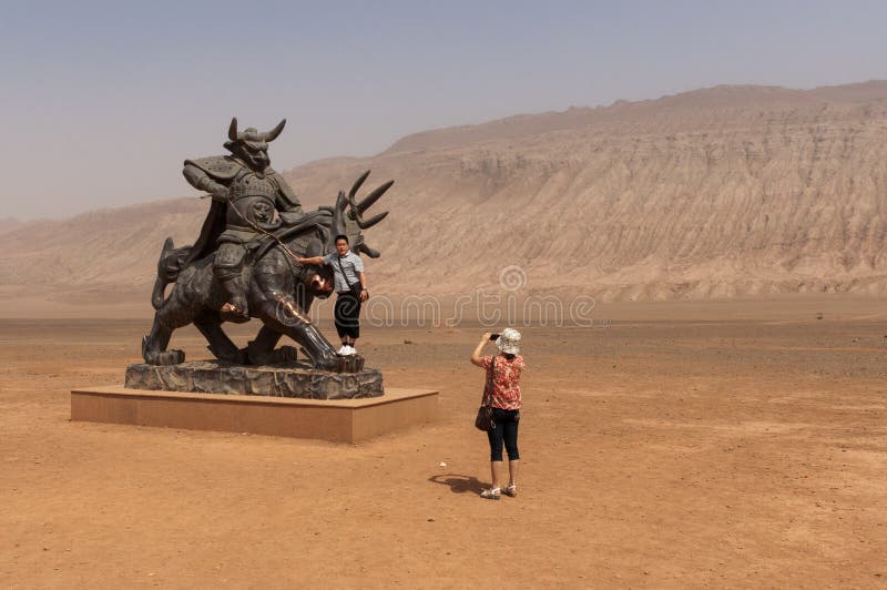 Kinesiska turister som framme tar bilder av en staty nära de flammande bergen, Xinjiang fotografering för bildbyråer Kinesiska turister som framme tar bilder av en staty nära de flammande bergen, Xinjiang fotografering för bildbyråer