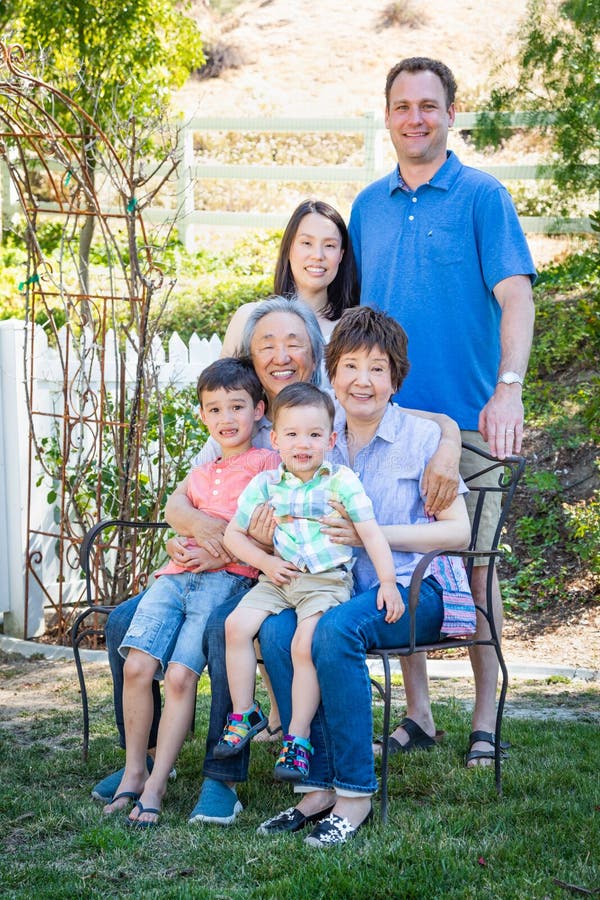 Kinesiskt Caucasian multietniskt familjsammanträde på bänk arkivfoto Kinesiskt Caucasian multietniskt familjsammanträde på bänk arkivfoto