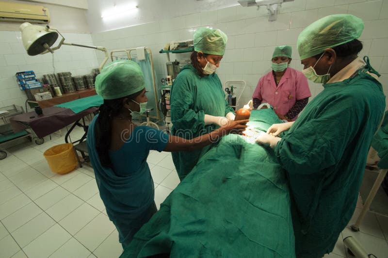 Kirurger och sjuksköterskor för en tubal ligation på en ung kvinna i Bihar, Indien royaltyfria bilder Kirurger och sjuksköterskor för en tubal ligation på en ung kvinna i Bihar, Indien royaltyfria bilder