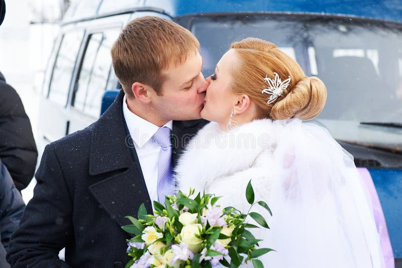 Kiss happy bride and groom on winter day